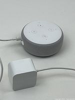 Amazon Echo Dot 3rd Gen smart speaker with connected power adapter on white surface.