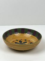 Front view of round ceramic serving bowl showing central floral pattern and striped rim