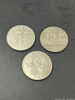 Three Canadian silver dollar coins displayed on black background, showing various historical designs and commemorations.