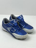 Pair of blue and white Easton boys soccer cleats positioned side by side showing the outer side profile and top view with laces tied.