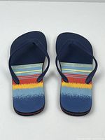 Top-down view of the pair of men's flip flops showing colorful striped design on footbed.
