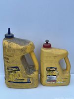 Two yellow plastic handheld Irwin Strait-Line chalk containers with handles. Larger container is for blue chalk, smaller for red chalk. Both show dirt and wear.