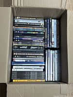 Top-down shot of box showing various DVD titles and genres packed inside.