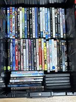 Top-down view of assorted DVDs arranged on their spine, showing titles like Milk, Show Me, Divergent, Flypaper, etc.