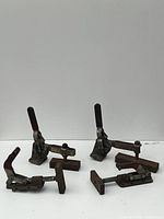 Four heavy duty DESTACO hold down clamps placed on white surface showing overall set condition.