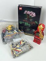 LEGO Blossom Tree boxed set, assorted LEGO pieces bagged, and a red ninja minifigure holding a golden sword