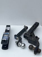 Lot of trailer hitch equipment including a Reese Clevis Mount, two trailer ball mounts, and a hitch ball, arranged on white background.