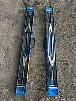 Pair of blue foldable metal sawhorses placed on gravel ground showing folded position and handles