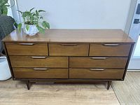 Front view of the walnut Mid Century Modern dresser showing six drawers and integrated wood handles.