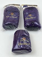 Three purple plush Crown Royal golf club head covers brand new and sealed in clear plastic packaging with Crown Royal branding on the attached cardboard labels.