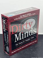 Brand new, sealed boxed adult party game titled 'Dirty Minds: The Game of Naughty Clues'. The box is mostly red with black and grey accents and white text.