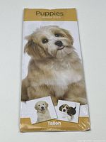 Front view of the calendar showing a large puppy photo and smaller images of three different puppies at the bottom, sealed in plastic.