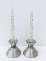 Front view of the pair of decorative acrylic glitter candles in metal holders on blank background.