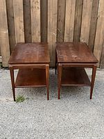 Pair of vintage solid wood side tables seen from a front angle, showing top surface and front legs.