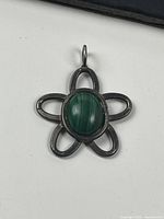 Front view of the sterling silver flower pendant with green oval stone.