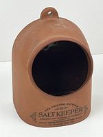 Front view of vintage terracotta salt keeper showing circular opening and printed branding.