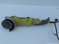 Side view of Ryobi angle grinder showing grinding wheel, body, and handle.