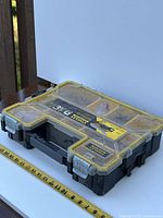 Top side view of Stanley FatMax storage box showing clear yellow lid with multiple compartments and metal latches.