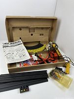 Contents of vintage Aurora AFX slot car racing track set including track pieces, controllers, cars, control panel, parts, and manual.