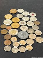 Top view of vintage coin assortment on black background showing coins of various sizes, metals, and denominations