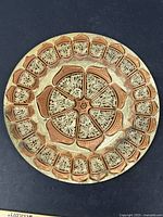 Top view of round copper decorative plate showing detailed floral cutout pattern and warm patina