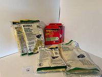Mixed assortment of Kenmore and 3M Filtrete vacuum bags, unopened and opened packs visible on white background