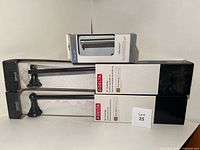 Photo of two Delta towel bars in bronze finish in original boxes and Amerock toilet paper holder in chrome finish box.