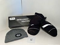 Photo of XL black heated gloves with white reflective stripes alongside the grey knit LED beanie hat and Intelligent Heating branded box.