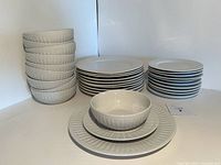 Overall group photo showing the 10 bowls stacked in a column, 10 dinner plates stacked in a column, and 10 salad plates stacked. One set with bowl on salad plate on dinner plate displayed in front.