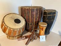 Photo showing the full set of 6 vintage percussion instruments including 4 drums, wooden flute-style instrument, and decorative shaker.