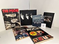 Photo showing all six books arranged standing and lying flat. Front covers visible including The Police photo book, Paul McCartney biography, several Beatles anthologies, and rock encyclopedias.