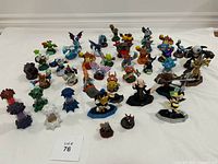 Overall view of approximately 40 Skylanders figures arranged on a white sheet, showing a wide variety of characters and associated traps.