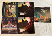 Five Styx vinyl LP albums laid flat showing cover art: Kilroy Was Here twice, Paradise Theatre, The Grand Illusion, and Equinox.