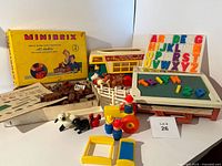 Photo showing the full lot including the Fisher Price School Days Desk, Play Family Camper with Little People figures and animals, and the Minibrix No. 2 Rubber Building Set with original box and manual.