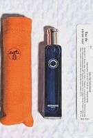 Photo showing the perfume bottle, orange fabric pouch, and informational leaflet, all branded HERMES.