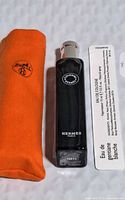 Photo showing black Hermes perfume spray bottle and orange protective pouch with label including product details.