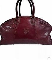Front view of large burgundy leather Boston bag showing embossed shield emblem and double handles.