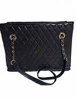 Front view of the black quilted leather handbag with gold chain and leather straps laid down.