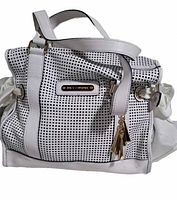 Front view of white Juicy Couture leather hobo bag showing perforated pattern, metal brand plaque and tassel detail on handle.