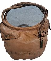 Front view of brown leather handbag showing braided handles, decorative studs, and leather body with some wear marks.