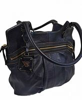 Front angle view showing black bag with zipper, handles, and branded charm.