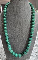 Front view of the 22 inch malachite bead necklace showing larger beads at the center and smaller beads toward the ends.