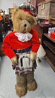 Front view of the 50 inch Scottish bear figurine dressed in red jacket and tartan kilt, standing upright.
