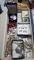Wide shot of assorted jewelry lot showing brooches, earrings, chains and boxed brooches