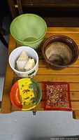 View of assorted ceramic pots, ashtray, and dish arranged on a wooden surface.