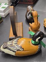 Lot of hand carved wooden birds and a small dog figurine displayed on a table, showing details of paint and ribbons.