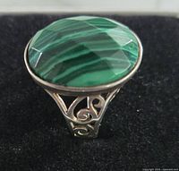 Close-up view of the oval faceted malachite stone set in a 925 silver ring showing banding pattern and faceting on the stone.