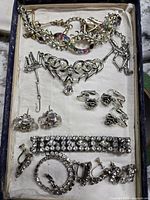 Overview of vintage jewelry lot including necklaces, bracelets, and screw-on earrings arranged in red velvet-lined box