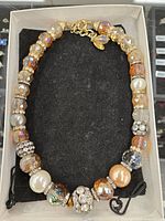 Amber colored crystal necklace displayed on black cushion inside a box, showing detailed bead arrangement and gold clasp.