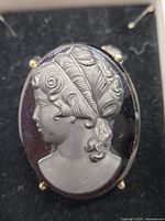 Front close-up of vintage mourning cameo brooch showing detailed right-facing female profile carved in jet and hematite.